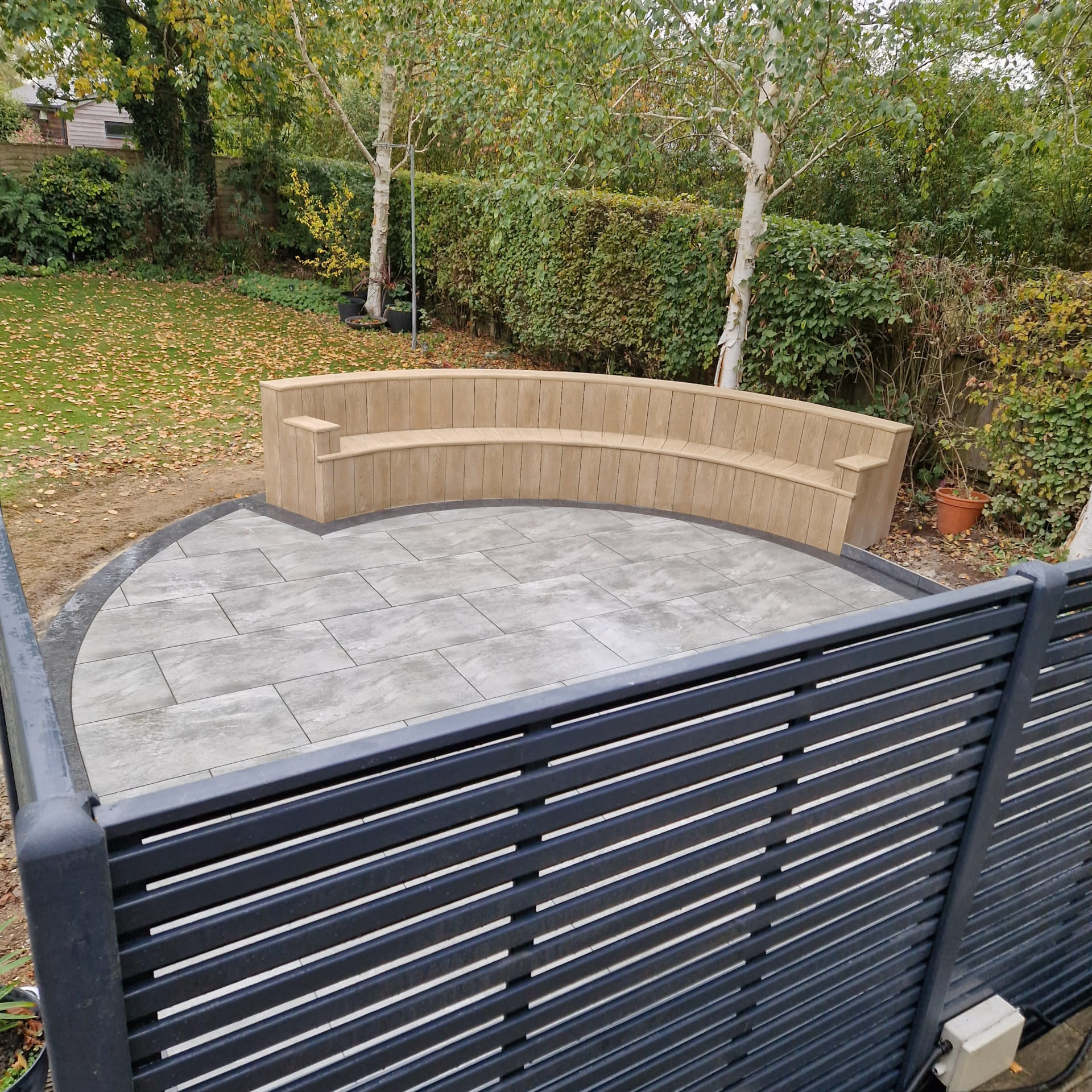 Green Room Gardens - porcelain patio with curved sleeper raised bed and slatted screen